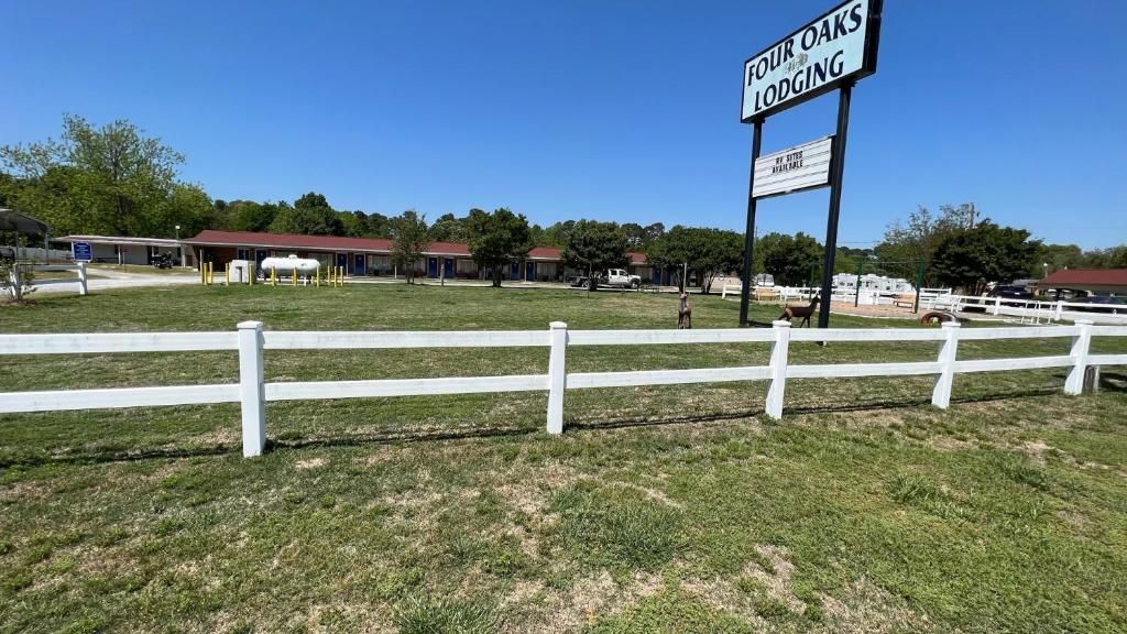 A fenced outdoor area with a sign for 'Four Oaks Lodging.'