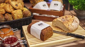 A variety of breads and pastries on a wooden table, including a loaf with a label and a knife.