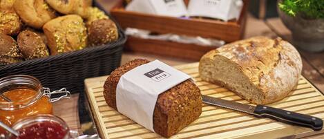 Diverse broden en gebak op een houten tafel, waaronder een brood met een etiket en een mes.