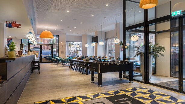 Un espacio interior moderno con mesa de billar, zona de estar y mostrador de recepción.