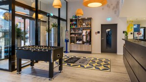 Un vestíbulo moderno con una mesa de fútbol de mesa, un mostrador de recepción y una tienda de ropa.