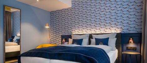 Una habitación de hotel moderna con una cama grande, un espejo, una mesita de noche y una pared con diseño.