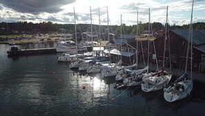 Un puerto deportivo con varios veleros amarrados, rodeado de edificios y una masa de agua tranquila.
