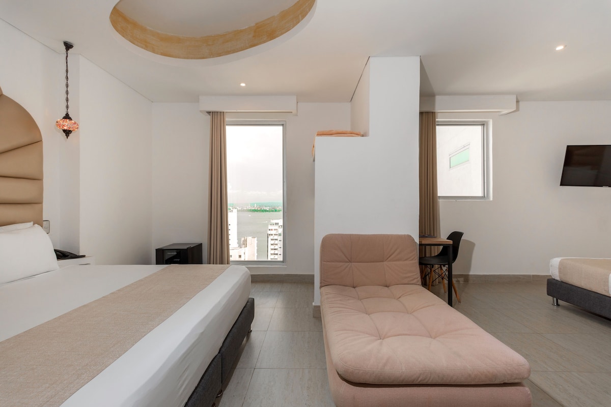 Una habitación de hotel moderna con una cama, un sofá, un escritorio y un televisor.