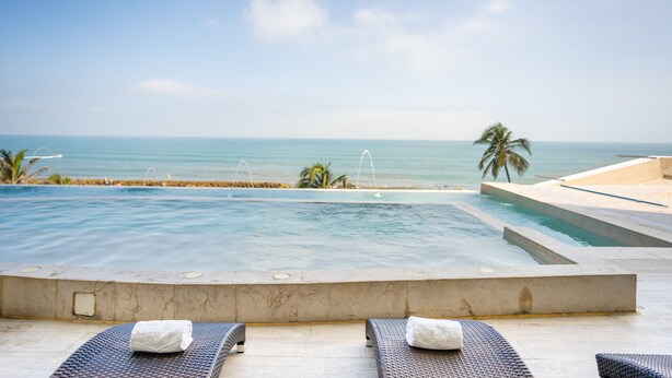 Un espace aménagé au bord de la piscine, avec des chaises longues et une vue sur l’océan.