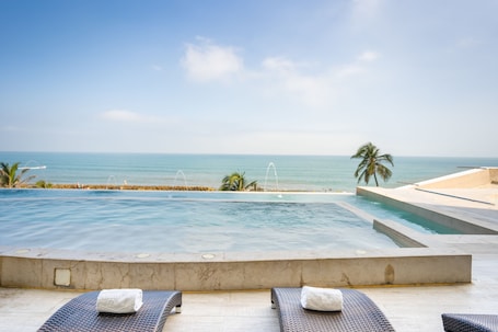 A poolside area with lounge chairs and a view of the ocean.