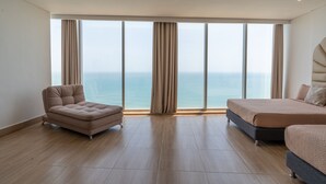 Une chambre d’hôtel moderne dotée d’une grande fenêtre, d’un canapé, d’un lit et offrant une vue sur la mer.