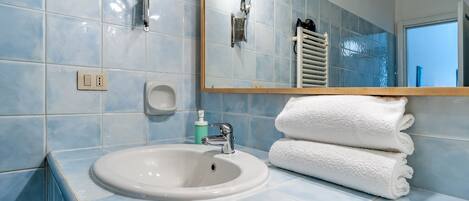 A bathroom with a sink, mirror, and towel rack.