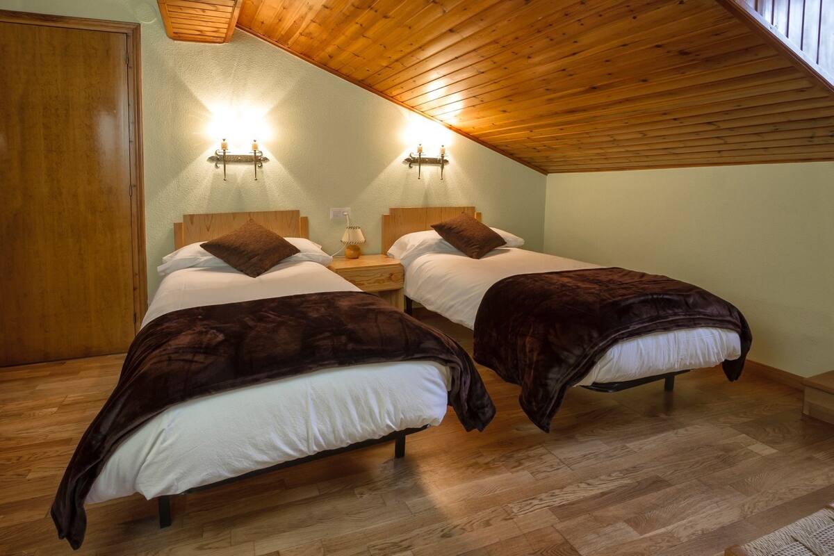 Un dormitorio con dos camas, suelo de madera y techo inclinado.
