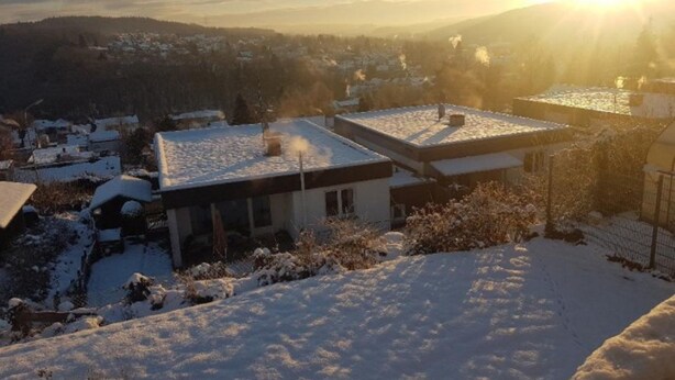 A residential area with houses covered in snow, a clear sky, and the sun setting in the background. - Ferienwohnung Auszeit (Wiehl)