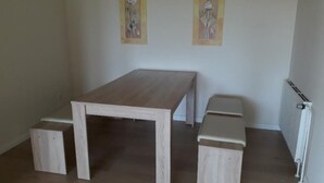 A room with a wooden table and benches, a radiator, and two wall-mounted artworks. - Ferienwohnung Auszeit (Wiehl)