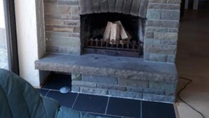A stone fireplace with a framed painting of sunflowers above it. - Ferienwohnung Auszeit (Wiehl)