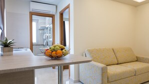 A modern living room with a sofa, a dining table with a fruit bowl, and an air conditioning unit. - Buono BB (Naples)