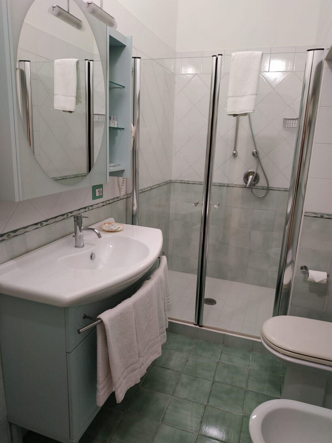 A bathroom with a sink, mirror, shower, and toilet.
