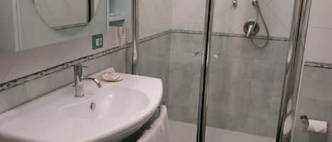 A bathroom with a sink, mirror, shower, and toilet.