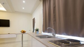 A modern kitchen with a built-in stove, a sink, and a flat-screen TV mounted on the wall. - Buono BB (Naples)