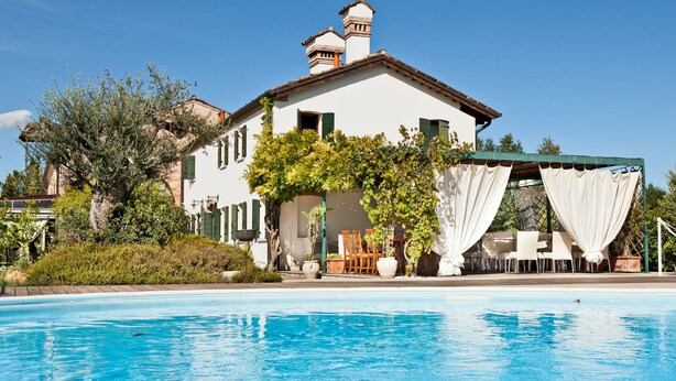 A poolside area with a white building, green shutters, and outdoor seating. - Do Ciacole in Relais (Mira)