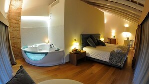 A modern hotel room with a large bed, a built-in bathtub, and a wooden floor. - Do Ciacole in Relais (Mira)