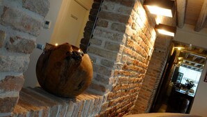 A rustic interior with exposed brick walls, a wooden barrel, and a modern light fixture. - Do Ciacole in Relais (Mira)