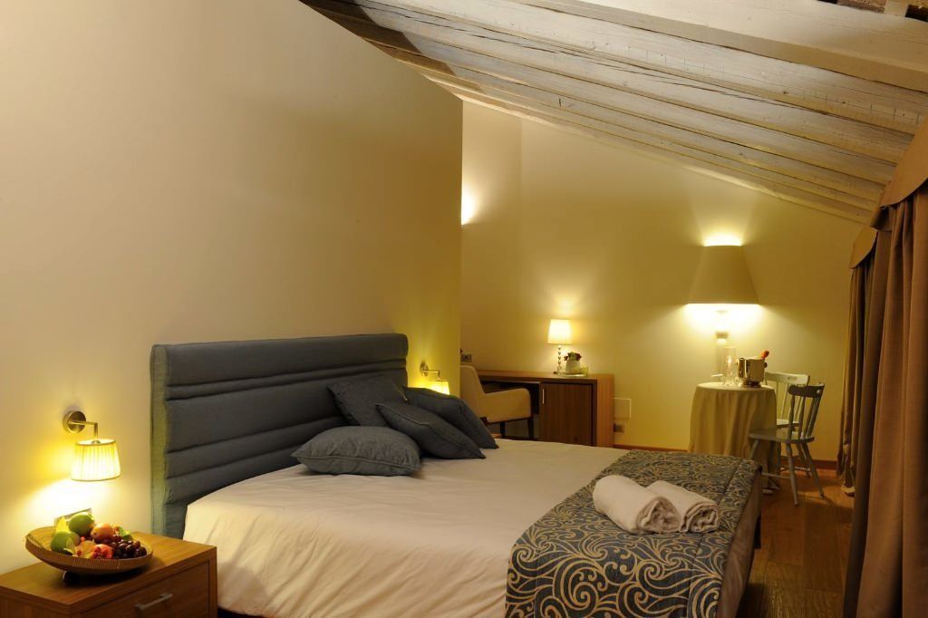 A hotel room with a large bed, bedside tables, a desk, and a chair.