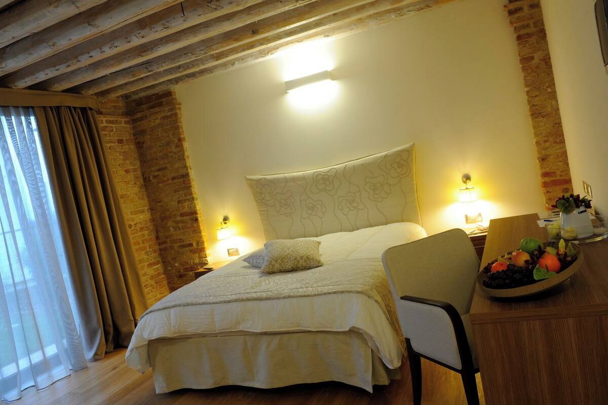 A hotel room with a large bed, a wooden desk, and a fruit bowl.