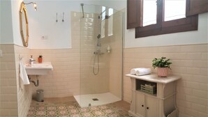 A bathroom with a shower, sink, and a cabinet with a plant.