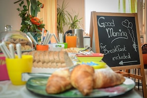 Una mesa de desayuno con croissants, una cafetera y un cartel que dice 'Good Morning for Breakfast included'.