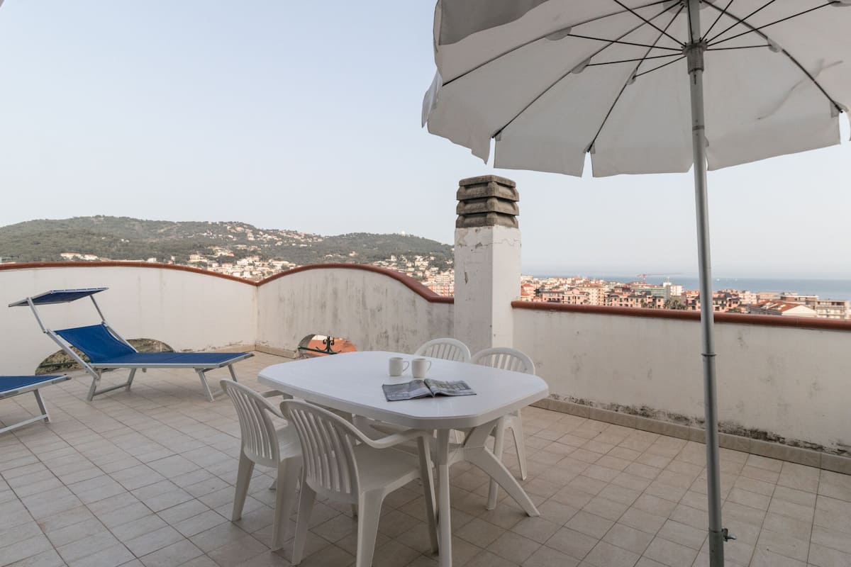 Una terraza con mesa, sillas y sombrilla.