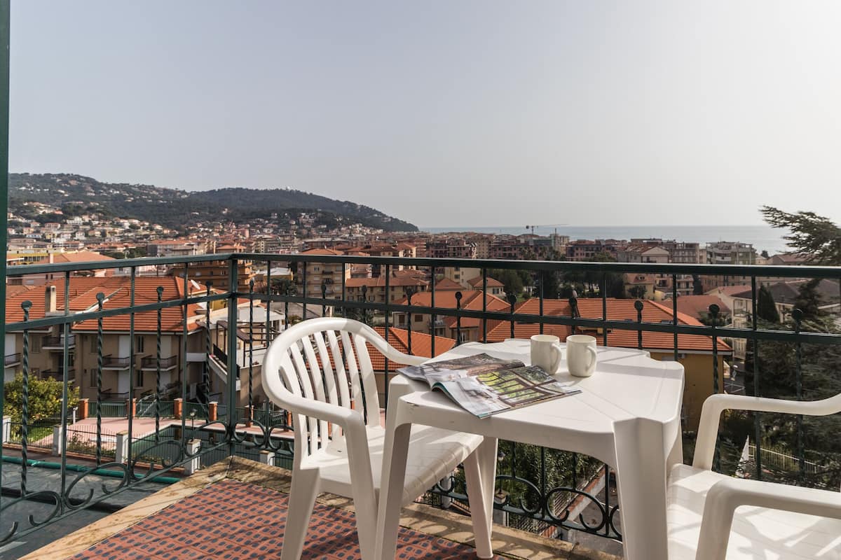 Un balcón con mesa y sillas que da a una vista panorámica de la ciudad costera.