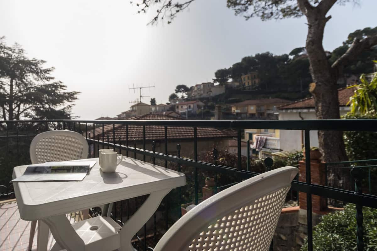 Un balcón con mesa y sillas, con vista a una zona residencial con casas y árboles.