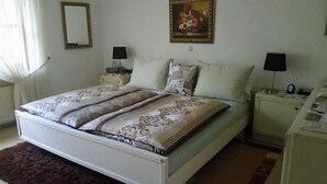 A bedroom with a bed, two bedside tables, a nightstand, a mirror, and a painting on the wall. - Ferienwohnung Wagner (Altenthann)