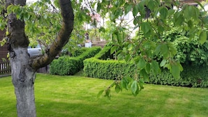 A well-maintained garden with a tree, neatly trimmed hedges, and a grassy lawn. - Ferienwohnung Wagner (Altenthann)
