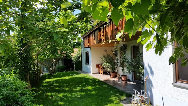 A house with a covered porch, potted plants, and a well-maintained lawn. - Ferienwohnung Wagner (Altenthann)