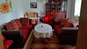 A living room with red sofas, a round coffee table, and a patterned rug. - Ferienwohnung Wagner (Altenthann)