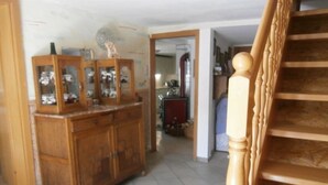 Una escalera de madera con barandilla que conduce a una habitación con suelo de baldosas y un mueble de madera con puertas de cristal.
