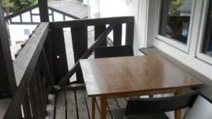Terraza de madera con mesa y sillas, con vistas a una zona residencial.