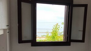 A room with a bed, a window with a view of the sea, and a white cabinet. - Villaggio Turistico Dea Cupra (Cupra Marittima)