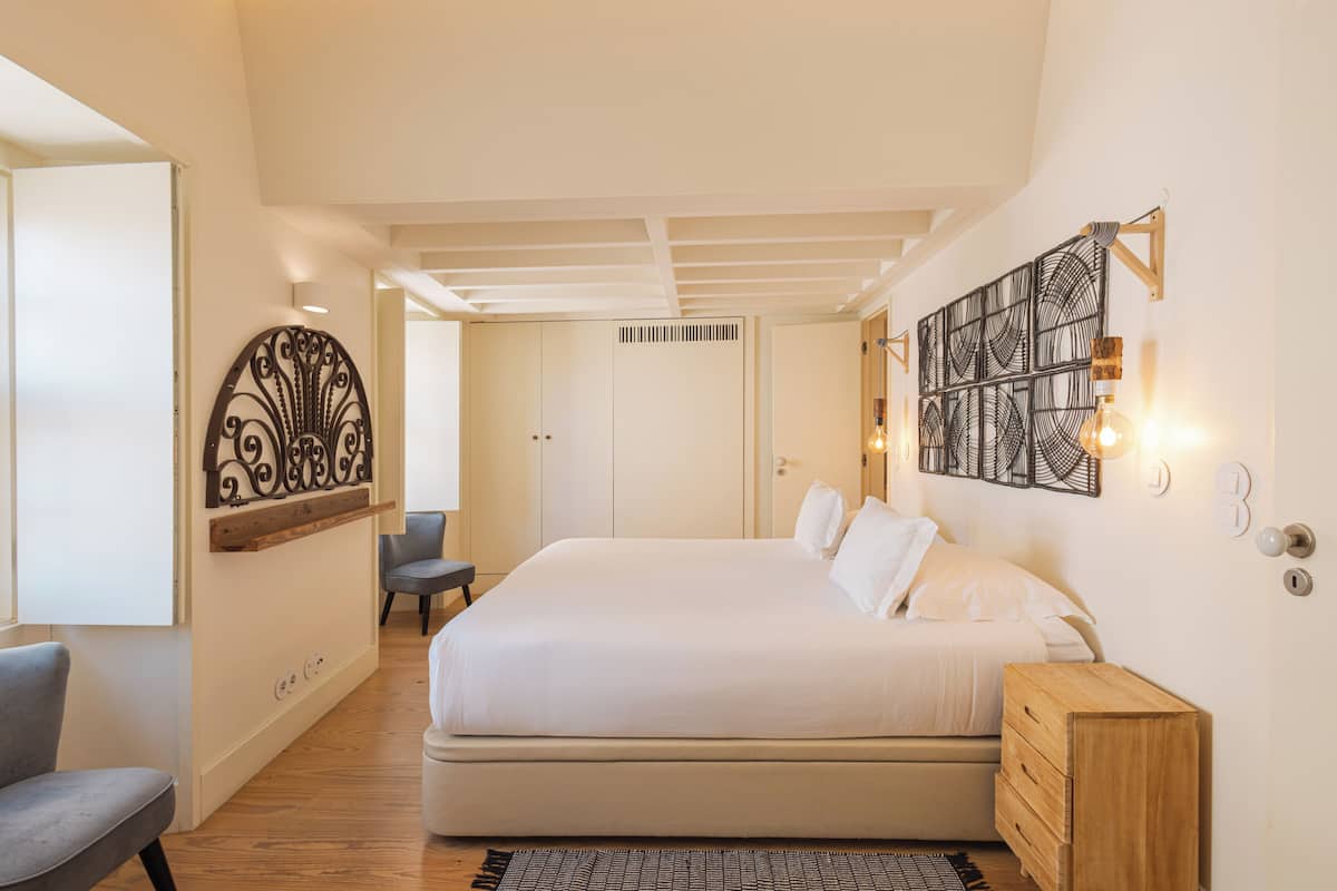 Une chambre à coucher avec un grand lit, une table de chevet en bois, une chaise et un élément décoratif mural.