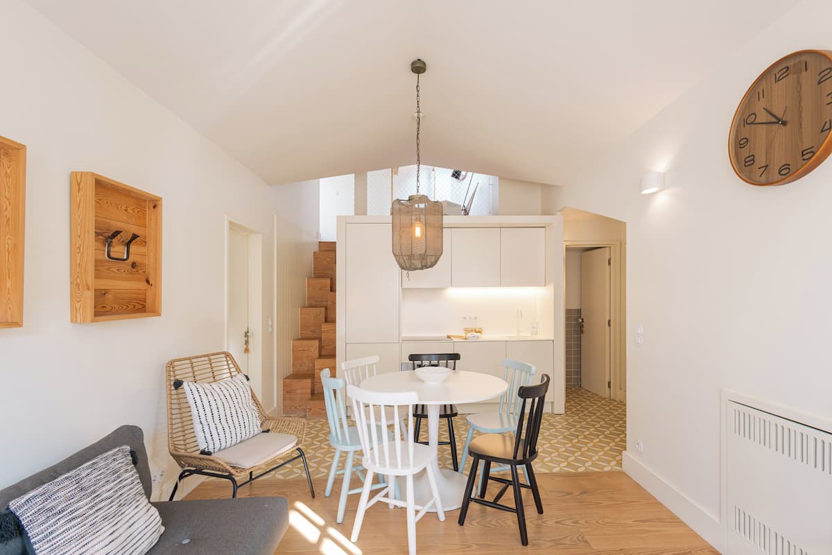 Un coin repas avec une table ronde et des chaises, un luminaire suspendu et une horloge en bois accrochée au mur.