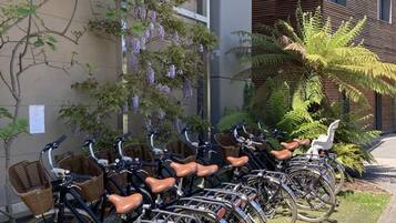 Varias bicicletas con cestas, estacionadas en un área pavimentada junto a un edificio de diseño moderno.