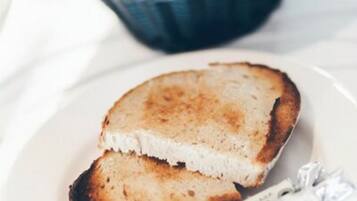A plate with toasted bread and a basket of pastries in the background.