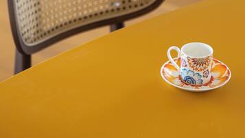 A chair with a woven backrest and a table with a cup and saucer.