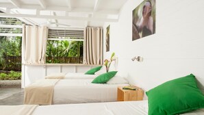 Un dormitorio moderno con dos camas, almohadas verdes, una mesita de noche de madera y una ventana con cortinas.