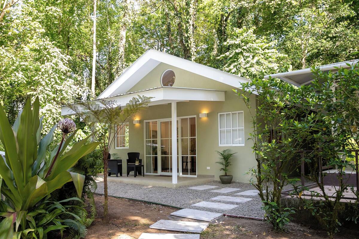 Ein Haus mit überdachter Terrasse, Essbereich und Garten mit Kiesweg.