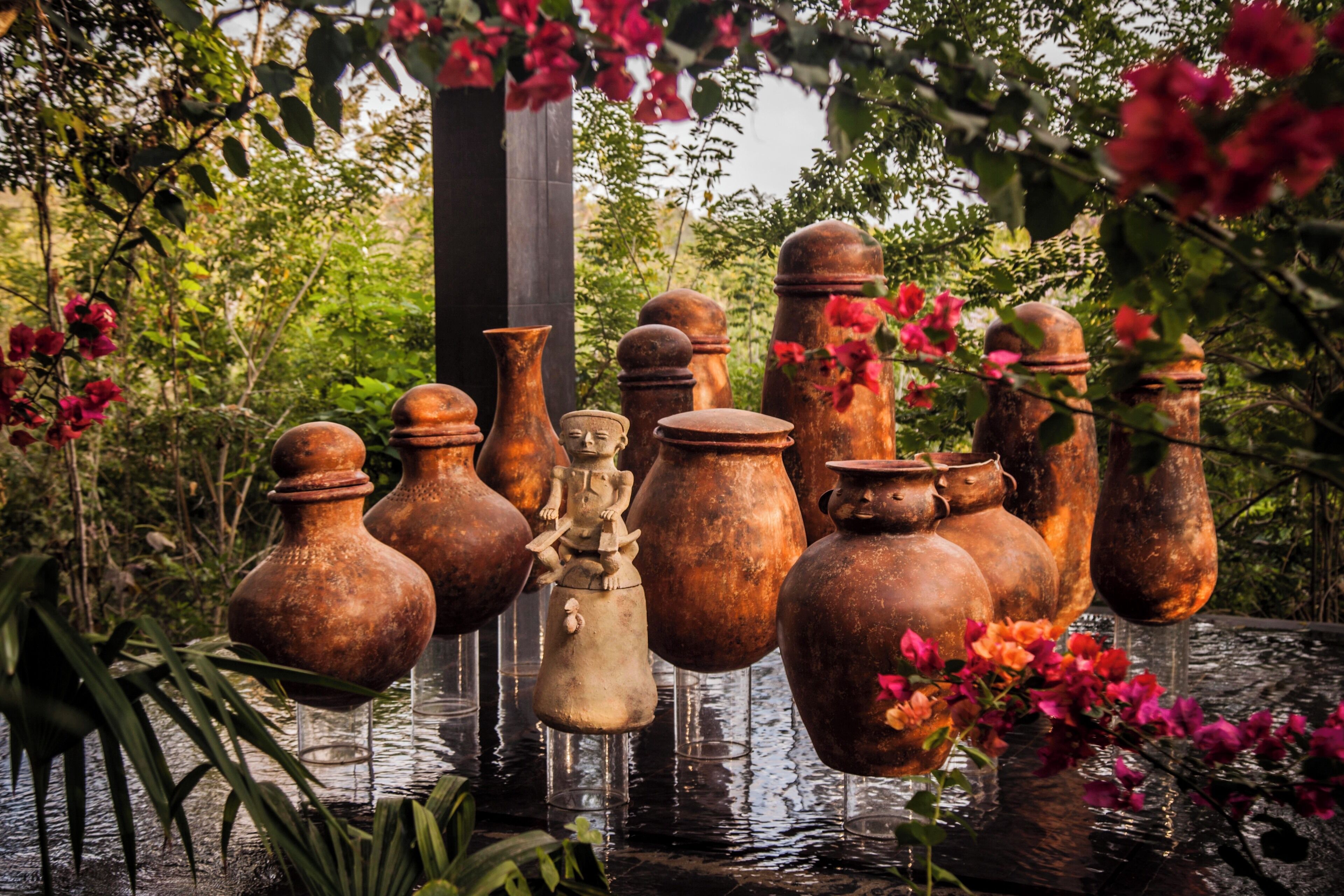 A collection of rustic pottery and sculptures in a garden setting.