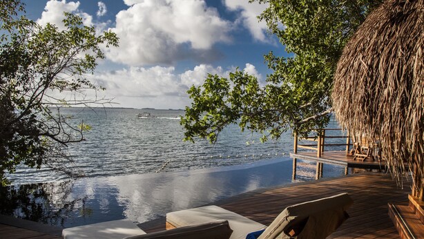 A wooden deck with lounge chairs overlooking a body of water, a thatched-roof structure, and a clear sky. - Las Islas (Cartagena)