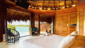 A bedroom with a large bed, a chair, and a view of the sea. - Las Islas (Cartagena)