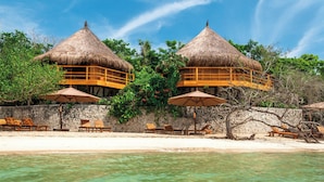 A beachside resort with thatched-roof overwater bungalows, clear turquoise water, and lounge chairs. - Las Islas (Cartagena)