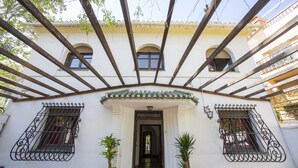 Un edificio con fachada blanca, un acceso cubierto y dos macetas.