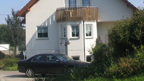 A two-story house with a balcony, a satellite dish, and a car parked in front. - Apartment im Dresdner Amselgrund (Dresden)